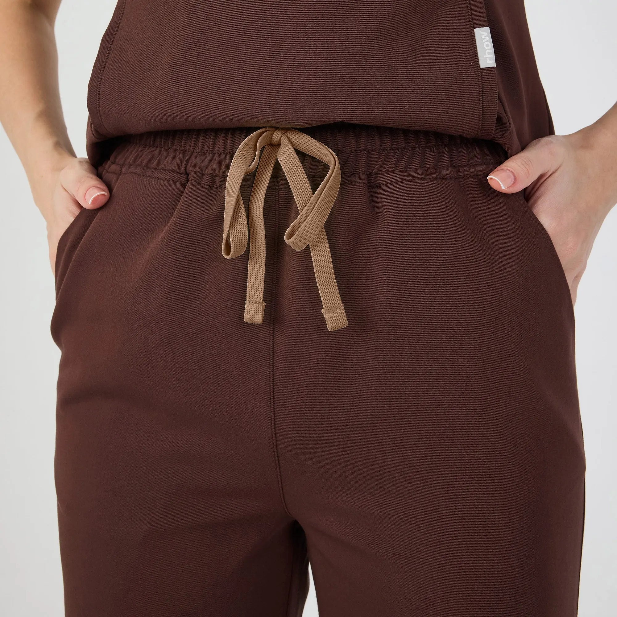 Koyu kahverengi scrub pantolon; lastikli bel ve kahverengi bağcık detayı