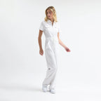 White scrub tulum, belted drawstring waist, front zipper, full-length legs.