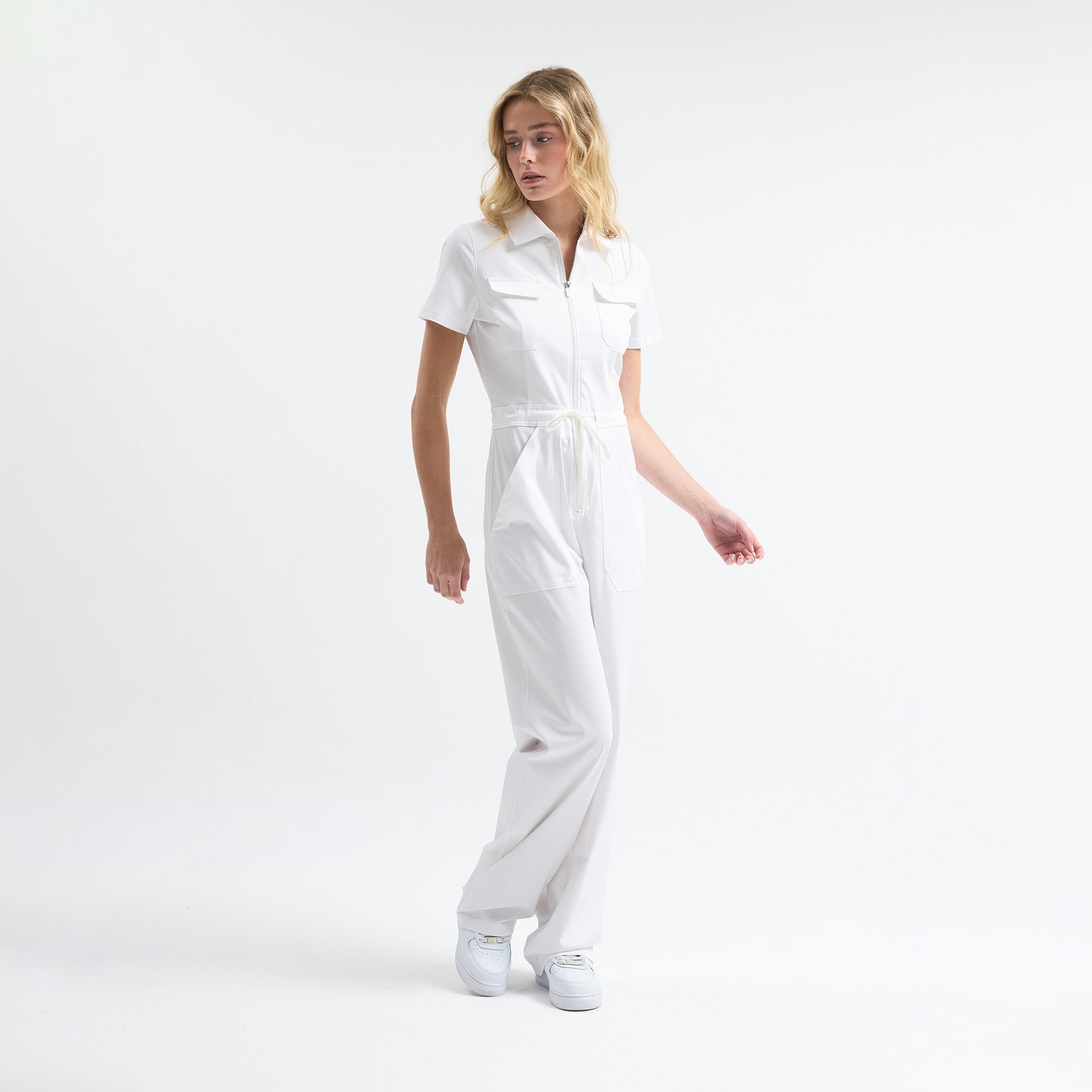White scrub tulum, belted drawstring waist, front zipper, full-length legs.
