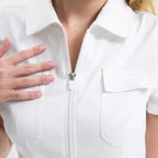 White scrub tulum close-up: front zipper and two chest pockets.