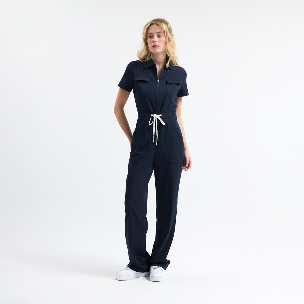 Navy scrub jumpsuit, front view with drawstring waist and patch pockets