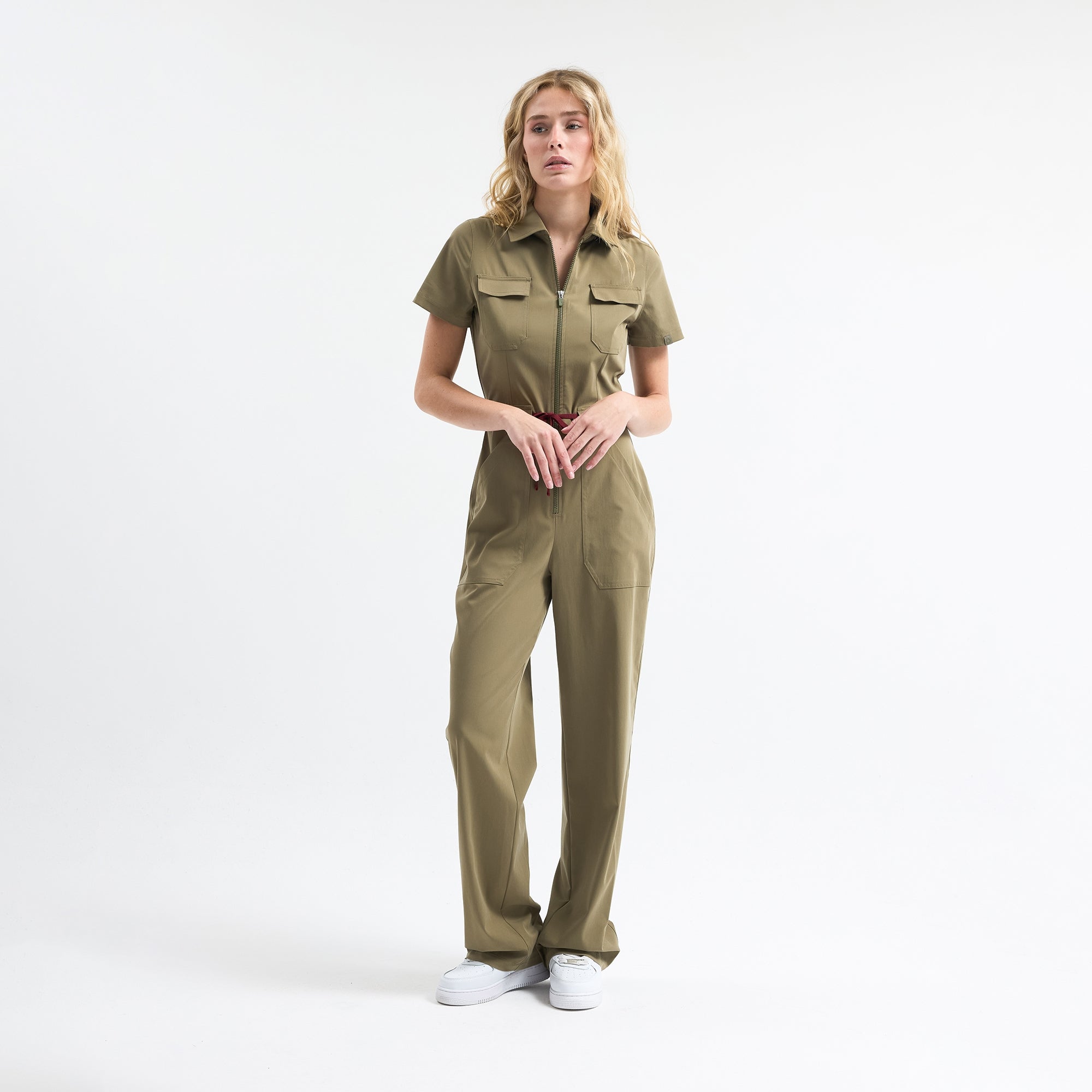 Hunter green scrub tulum on model, short sleeves, chest pockets, tie waist