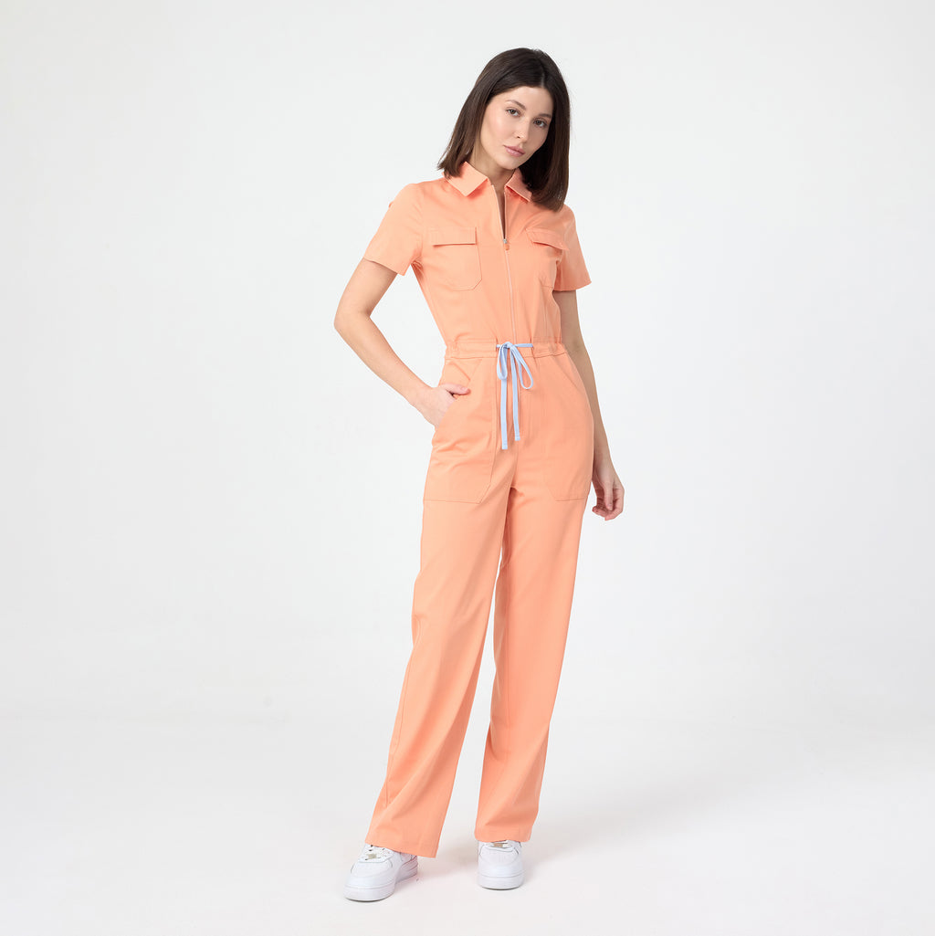 Tangerine scrub tulum with short sleeves, front zipper, and patch pockets