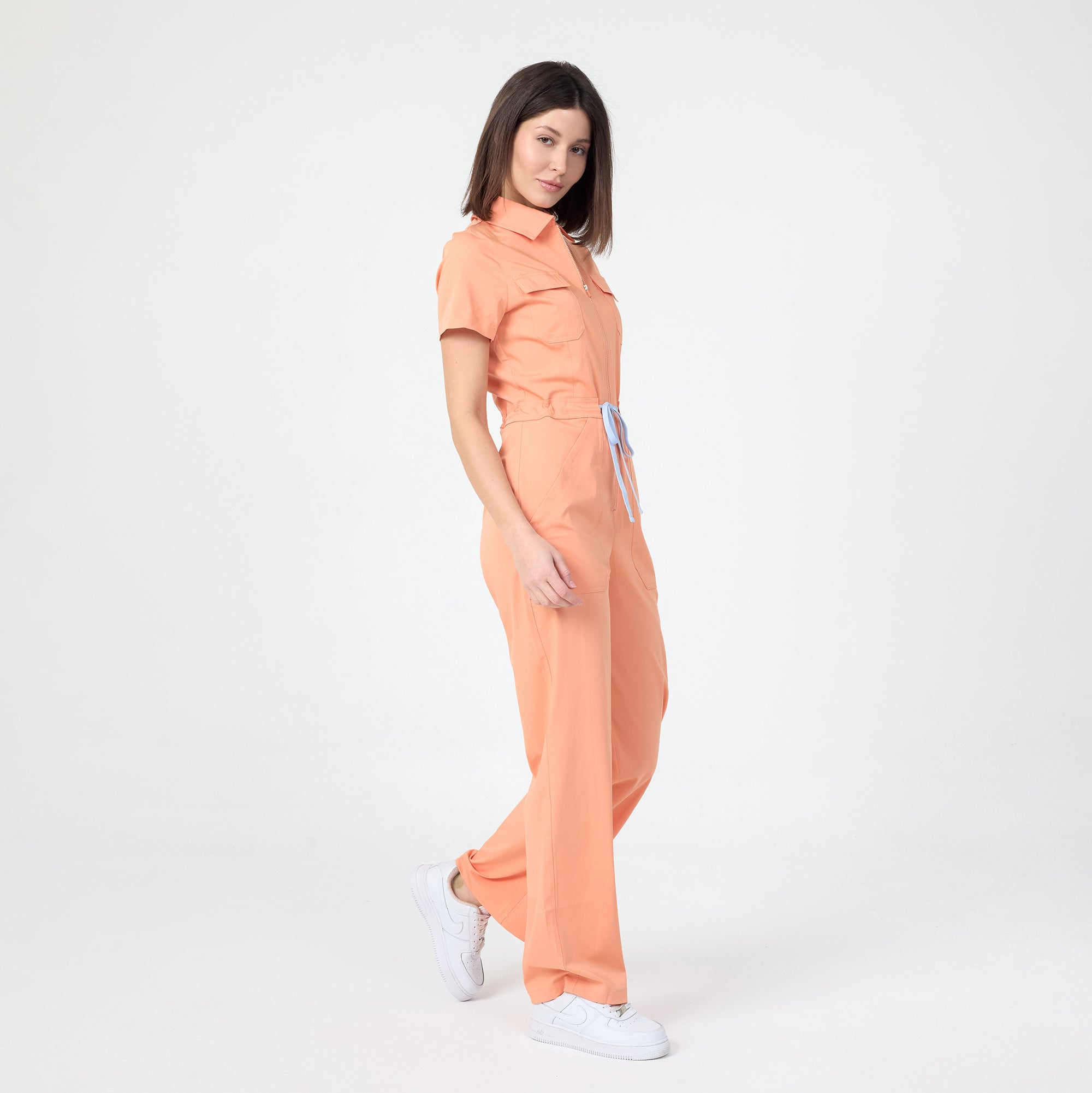 Tangerine scrub tulum with short sleeves, front zipper, and straight wide legs
