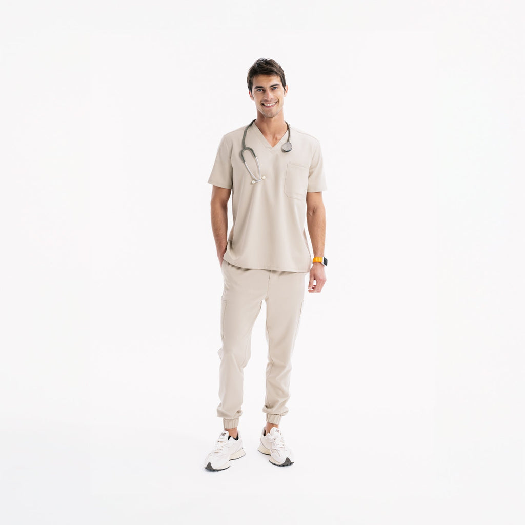 Açık bej jogger scrub pantolon; manşetli paça, belde bağcık ve cep detayları.