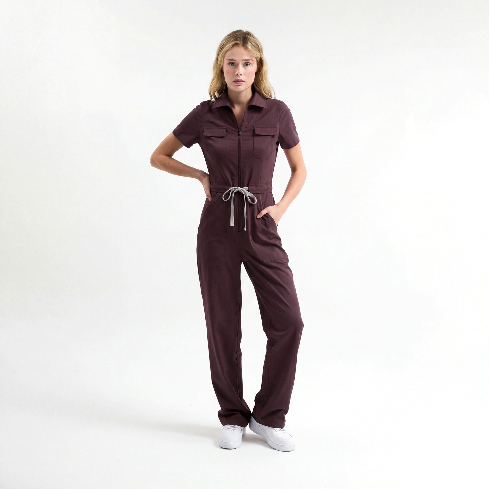 Bordo scrub tulum; kısa kollu, önden fermuarlı, belden bağcıklı pantolon paçası geniş