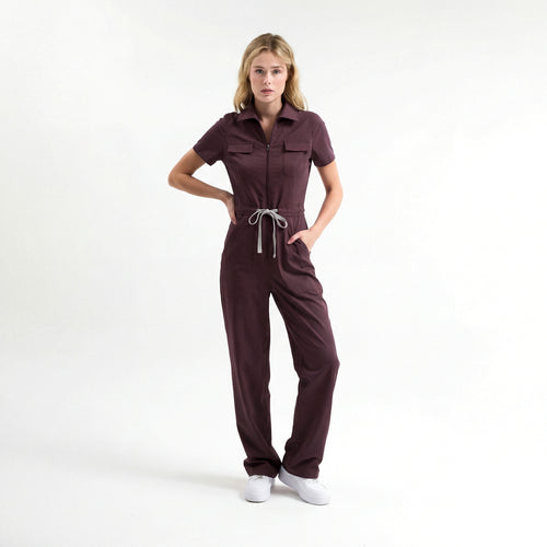 Bordo scrub tulum; kısa kollu, önden fermuarlı, belden bağcıklı pantolon paçası geniş