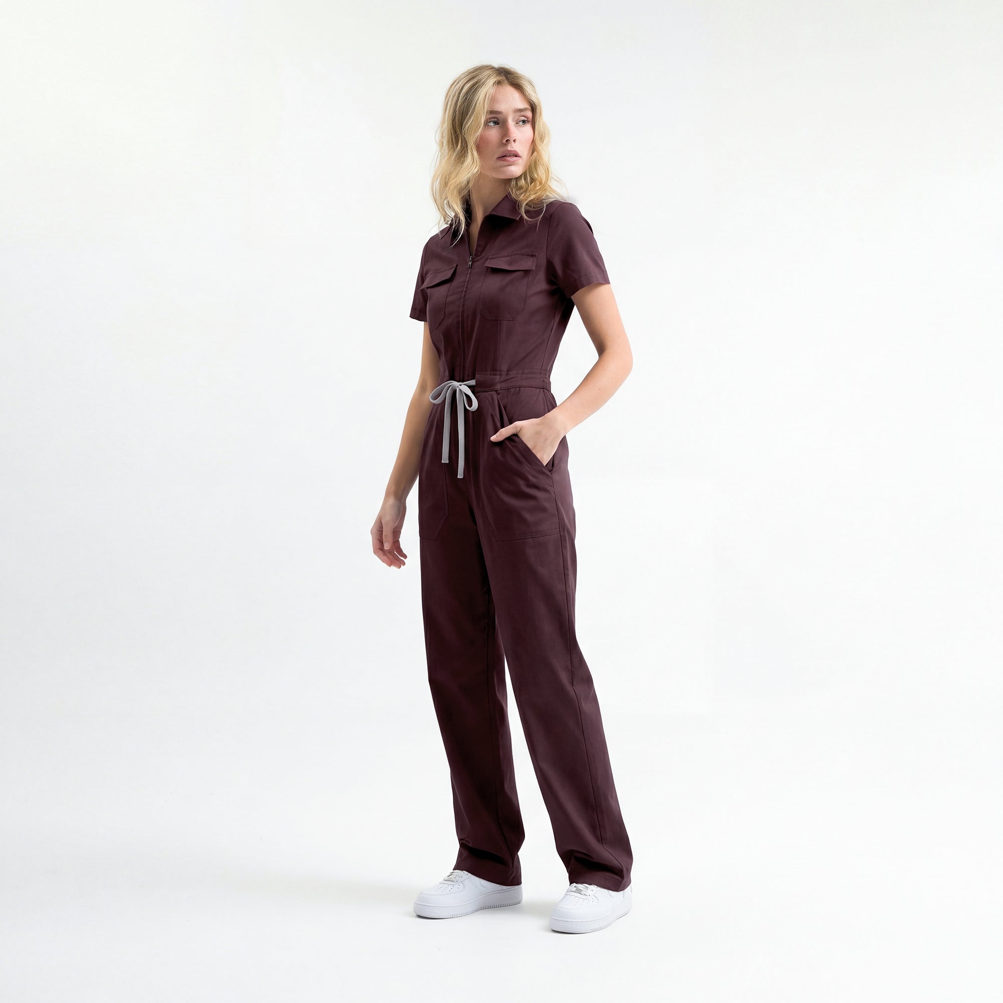 Bordo scrub tulum; kısa kollu, belden bağcıklı ve yan cep detaylı tam boy görünüm